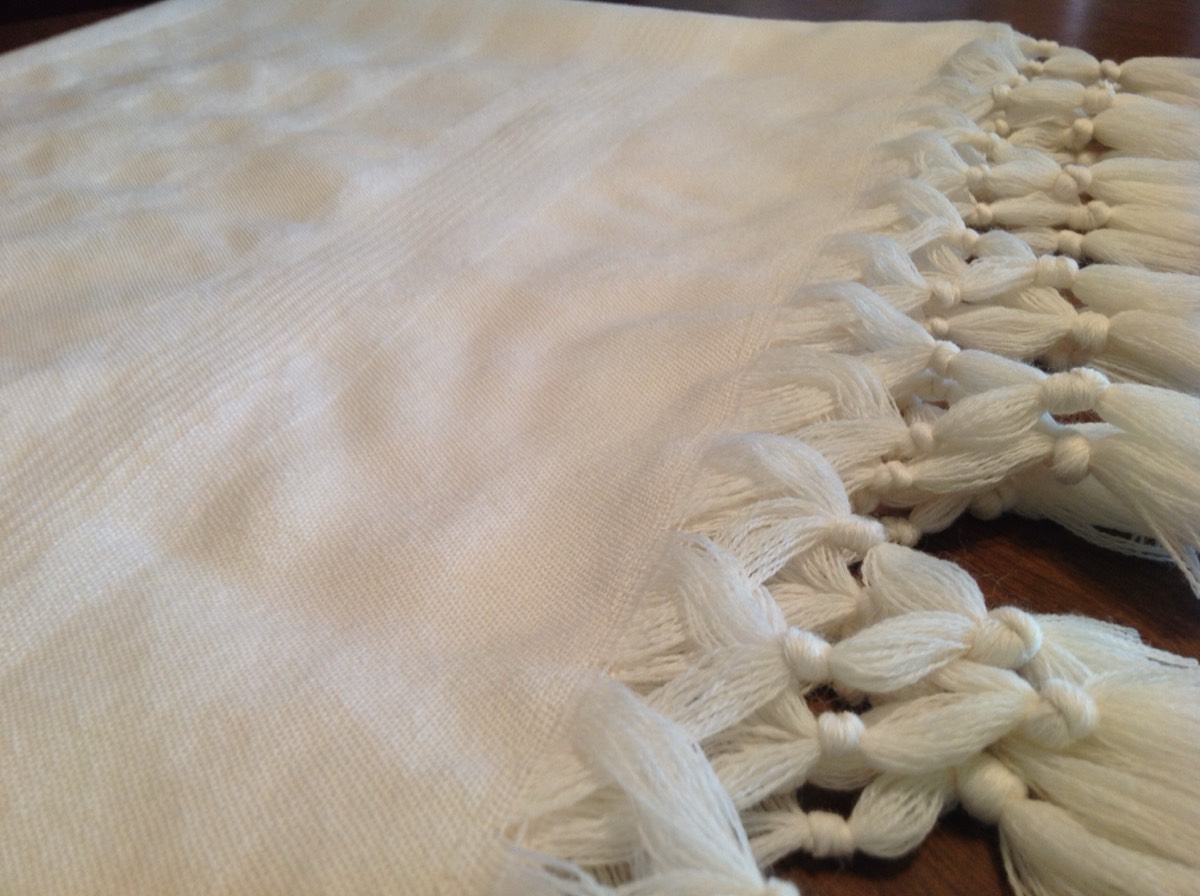 Detail of hand-knotted fringe on woven white fabric