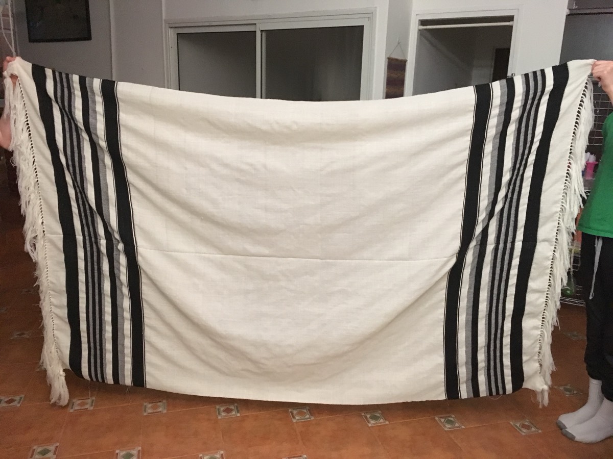 Full-size hand-woven tallit held open, showing black stripe pattern